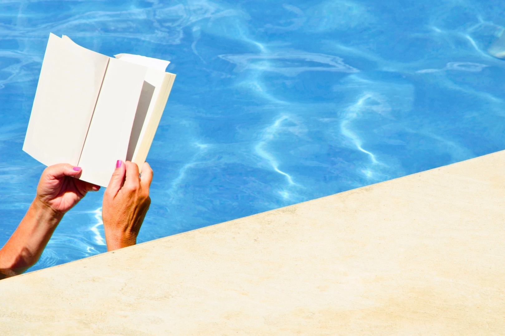 Person liest Buch im Pool